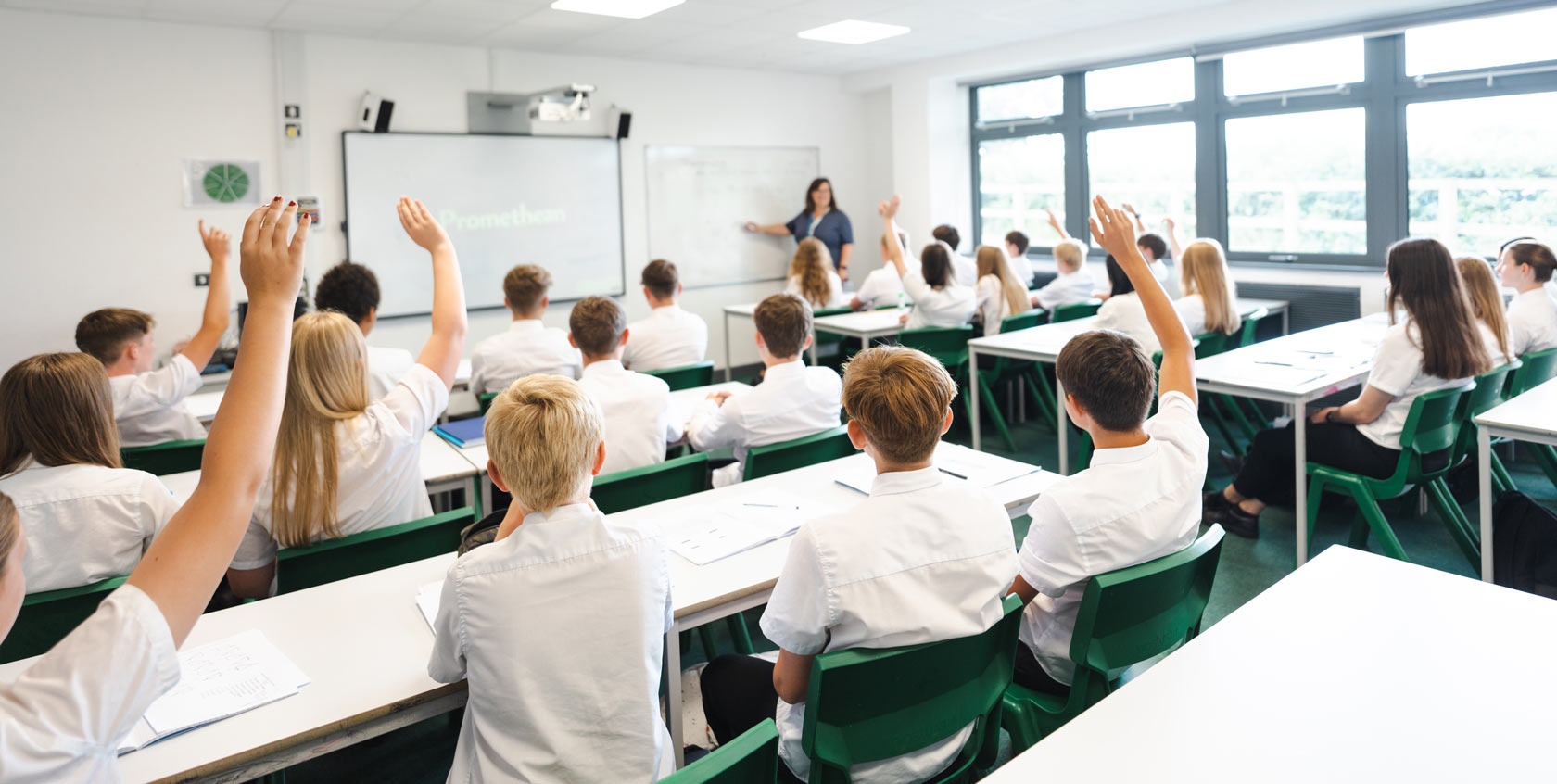 Students in classroom with hands raised